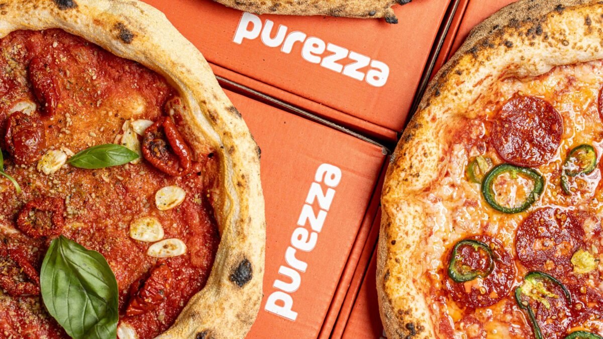Two Purezza pizzas overhead on stacked orange boxes, one margherita and one pepperoni
