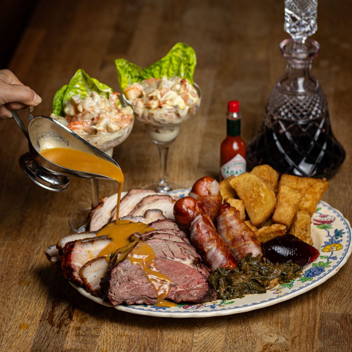 Gravy poured over a Red Dog Saloon carvery plate, prawn cocktails and a decanter behind
