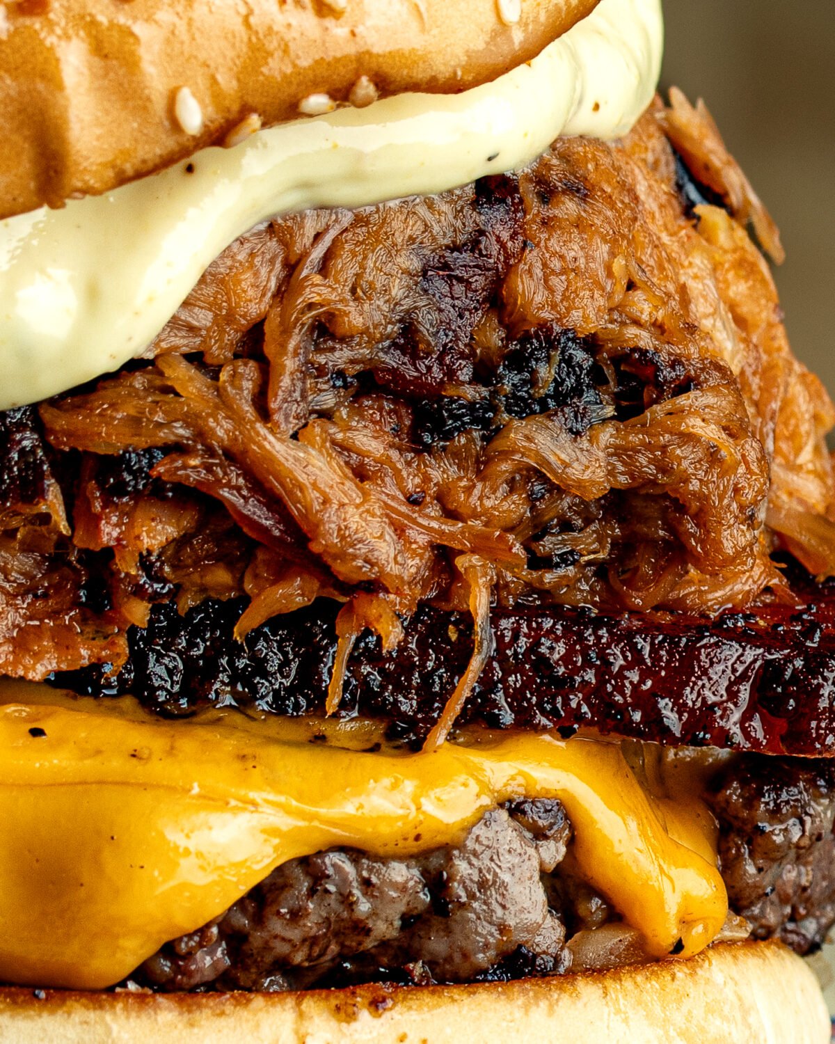 Close-up of a Red Dog Saloon burger loaded with pulled pork, burnt ends and melted cheese