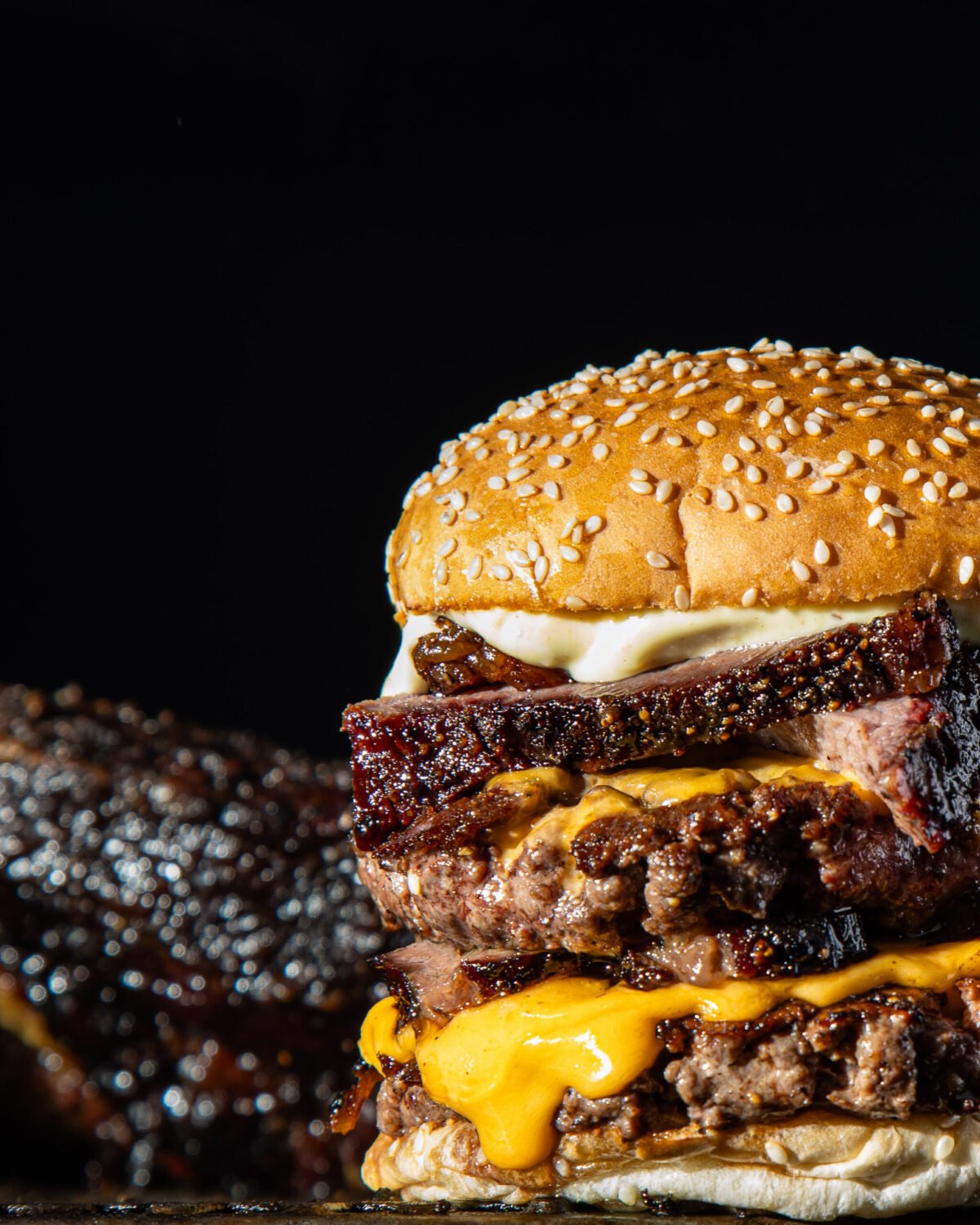 Red Dog Saloon double cheeseburger topped with burnt ends, a rack of ribs soft behind it