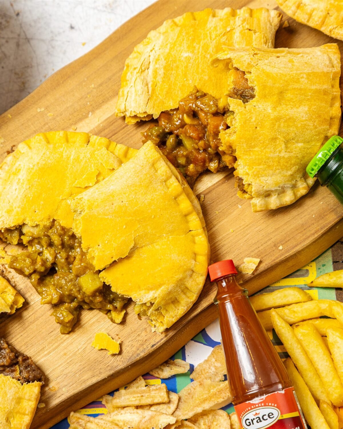 Overhead of a Jamaican patty opened to reveal the curried filling on a wooden serving board