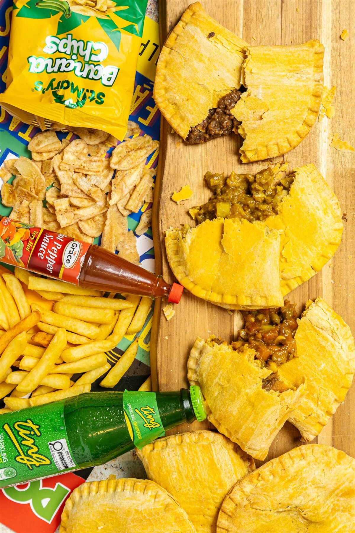 Jamaican patties served with fries, banana chips and a cold drink laid out as a full meal