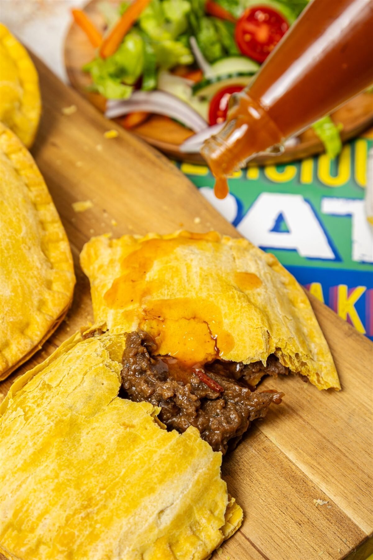 Pepper sauce poured over a Jamaican patty broken open to show the beef filling