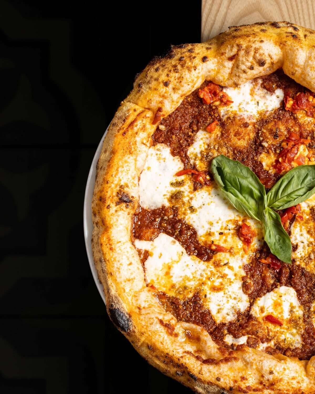 Lasagna pizza lit against a black half frame left open for campaign copy