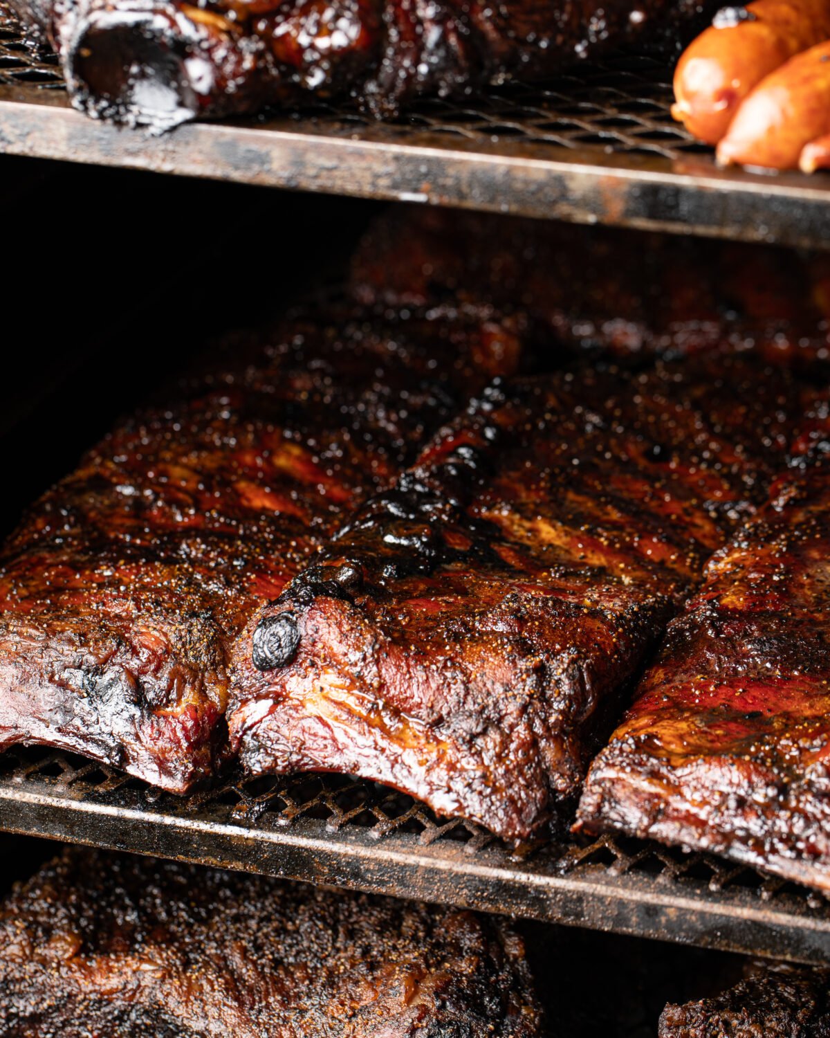 Close-up of glossy barbecue ribs on the rack, still sitting in the smoke