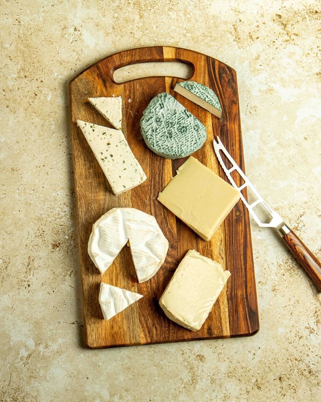 Overhead cheese board with blue, brie and hard cheeses on a wooden paddle
