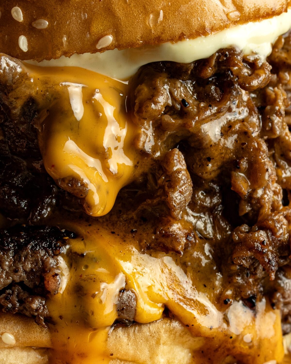 Close-up of a brisket burger with melted cheese and gravy running over the patty