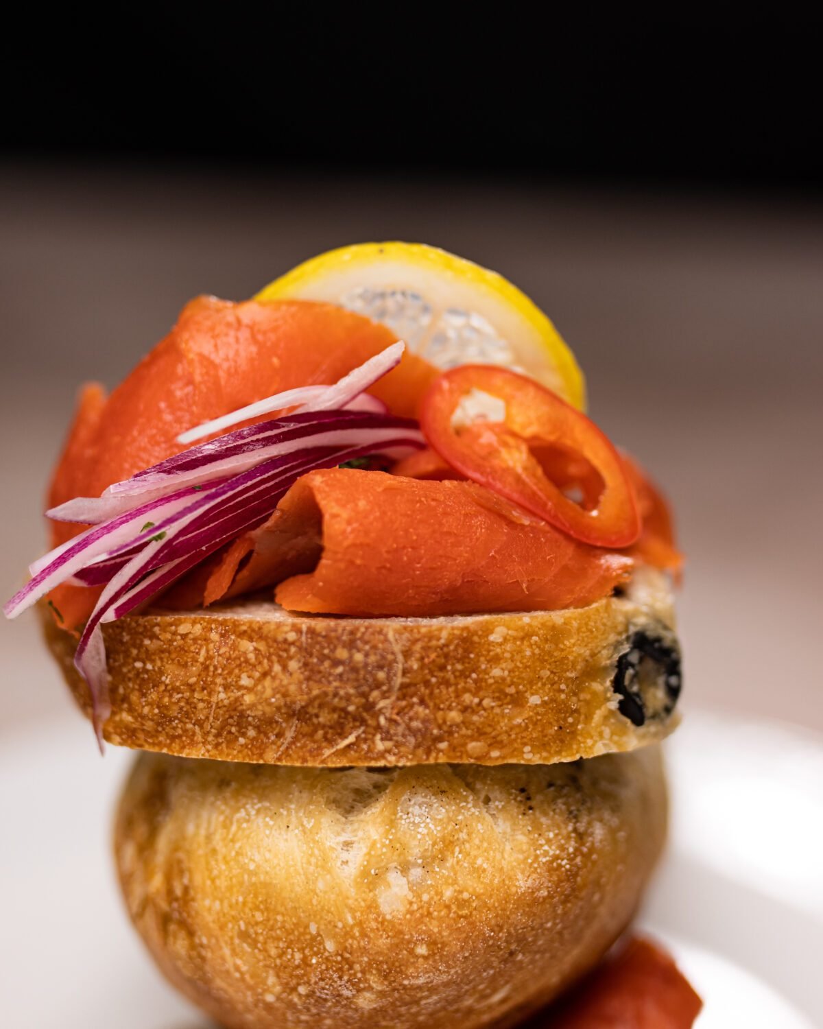 Smoked salmon and pickled red onion piled on a slice of sourdough with lemon