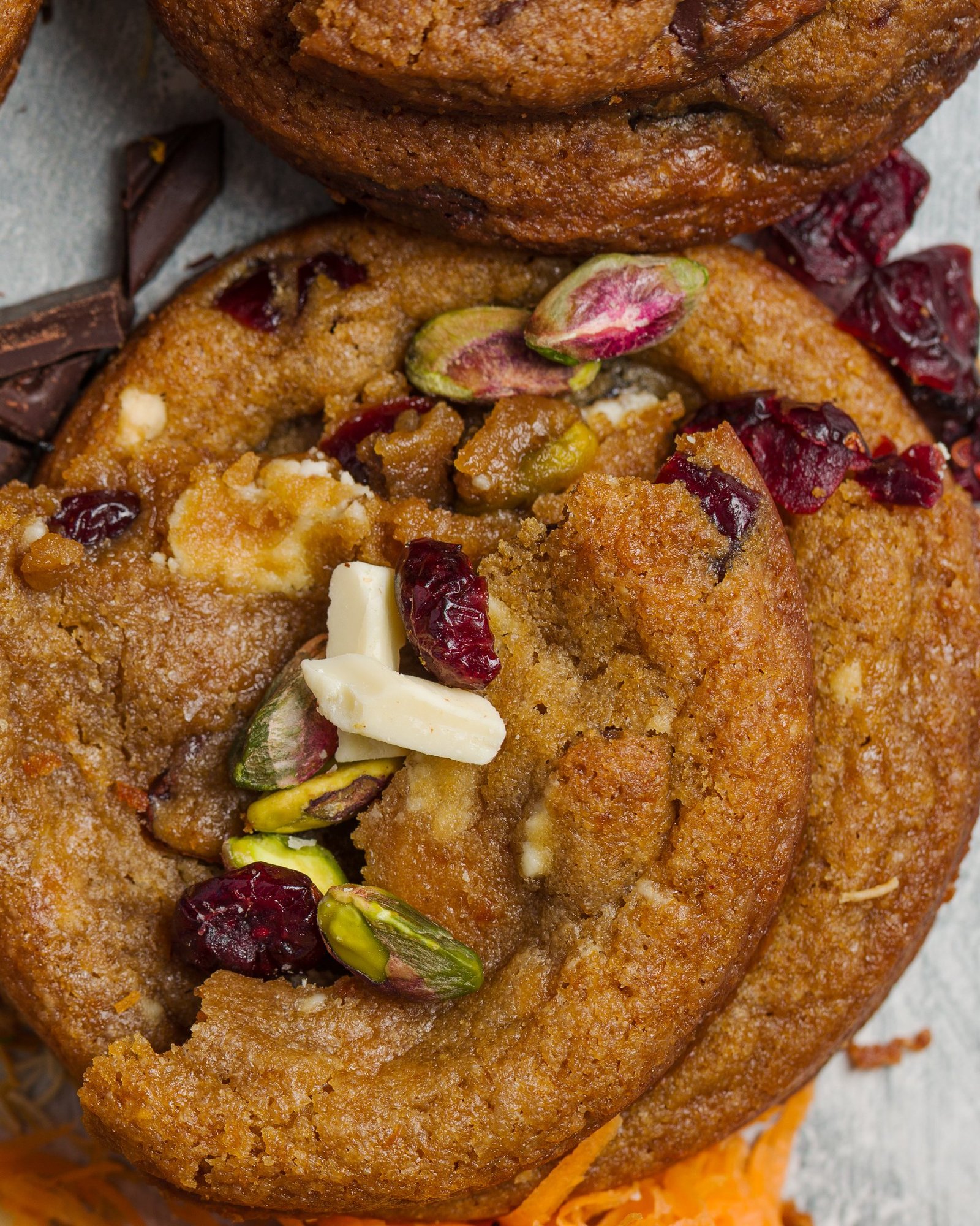 Macro photograph of a pistachio, cranberry and white chocolate cookie filling the frame, shot on a 100mm macro lens for an artisan cookie brand in Croydon.