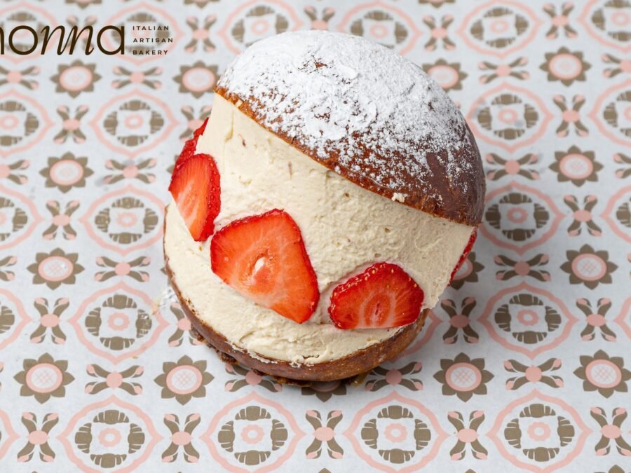 Strawberry maritozzo, a split brioche filled with cream with strawberry slices set into it and dusted with icing sugar, bakery photography for a Sicilian bakery in Holborn, London.