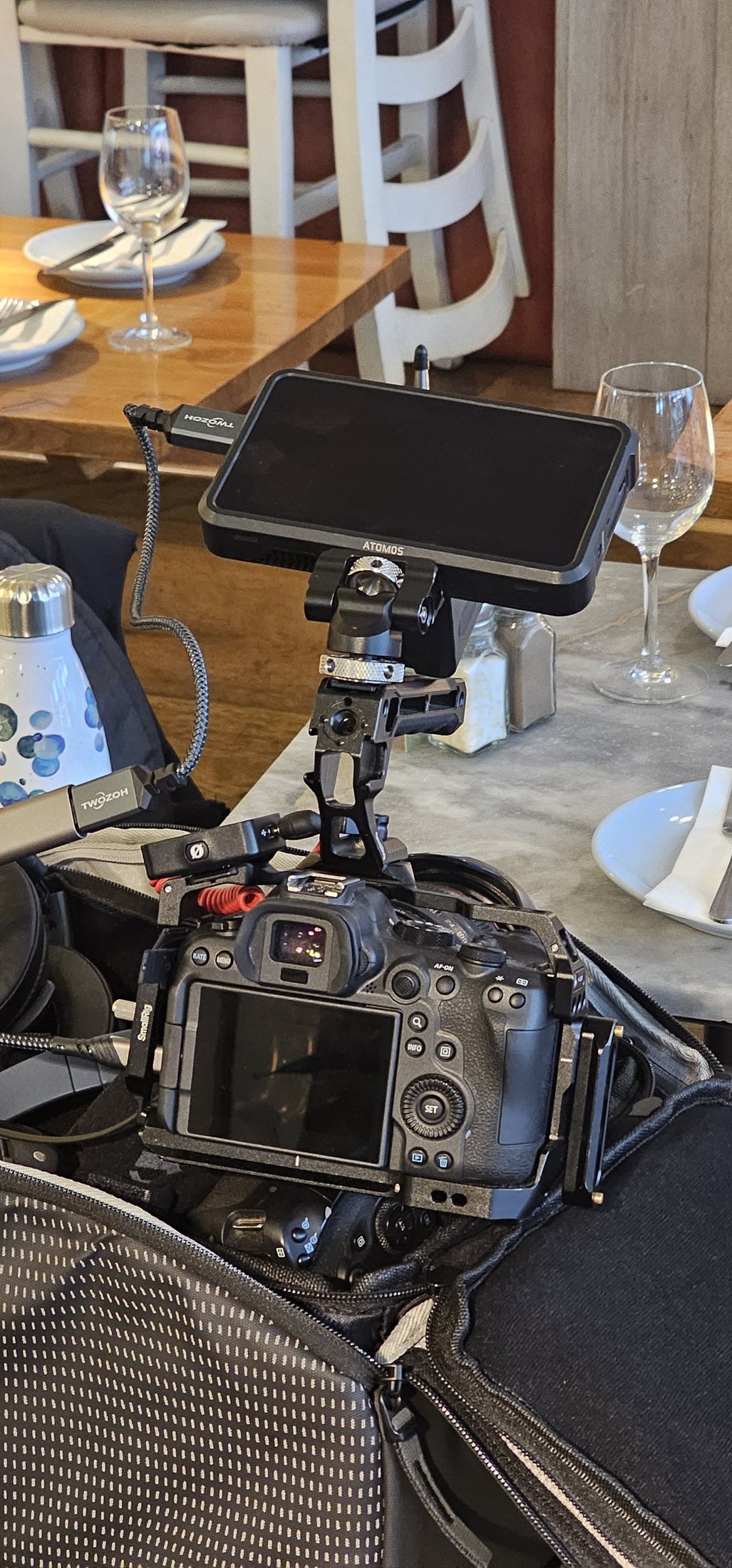 A camera rig built for a restaurant interview shoot, Canon body in a cage with a field monitor on top, set up in a London restaurant before service.
